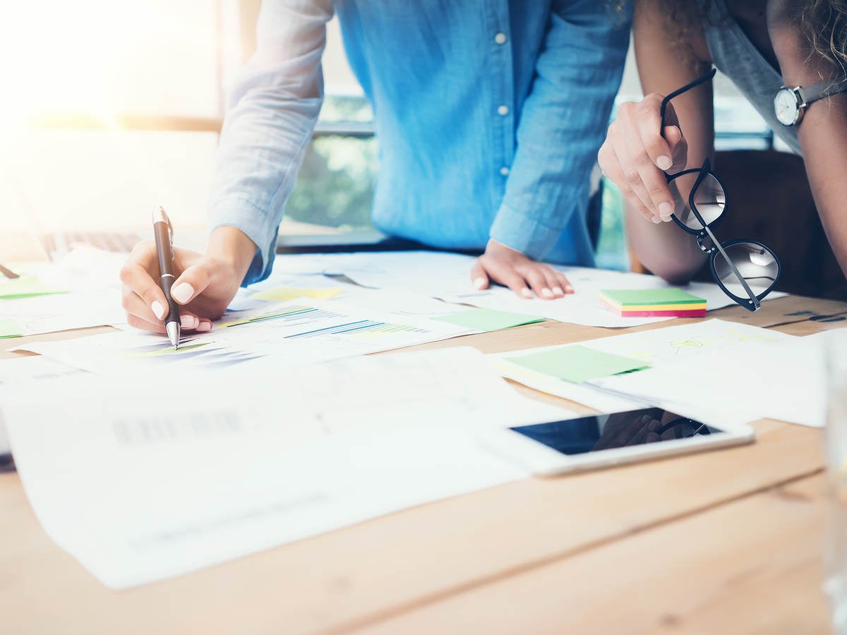 A man and a woman make notes on charts and graphs.